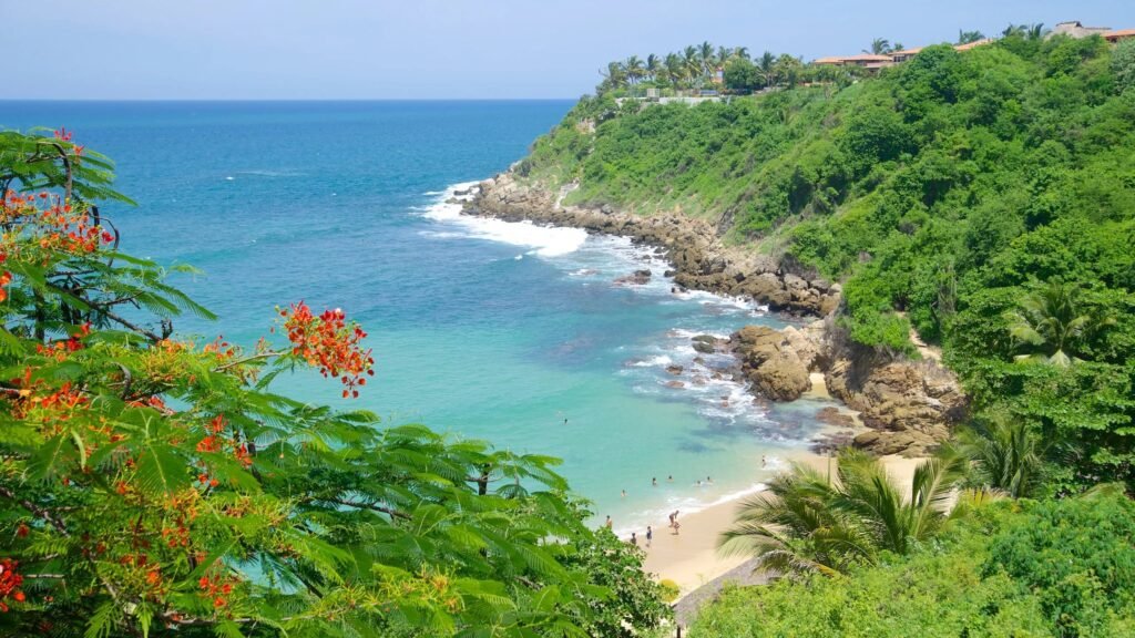 Scenic view of a tropical beach bay with turquoise water and lush green trees in Puerto Escondido Mexico