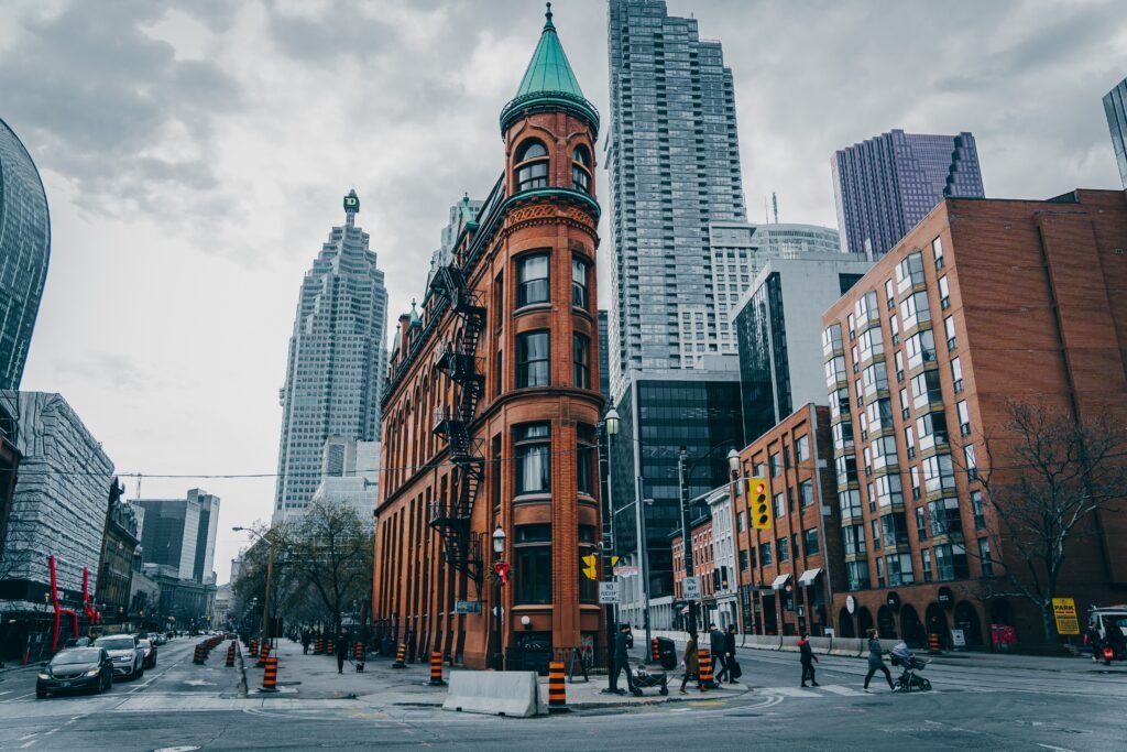The historic Gooderham Flatiron Building on a street corner with modern skyscrapers in Toronto