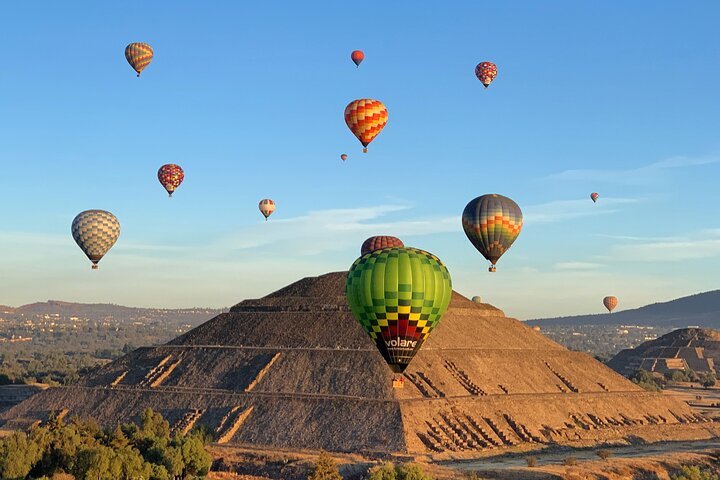 Teotihuacán ancient pyramids and hot air balloons flying over the landscape